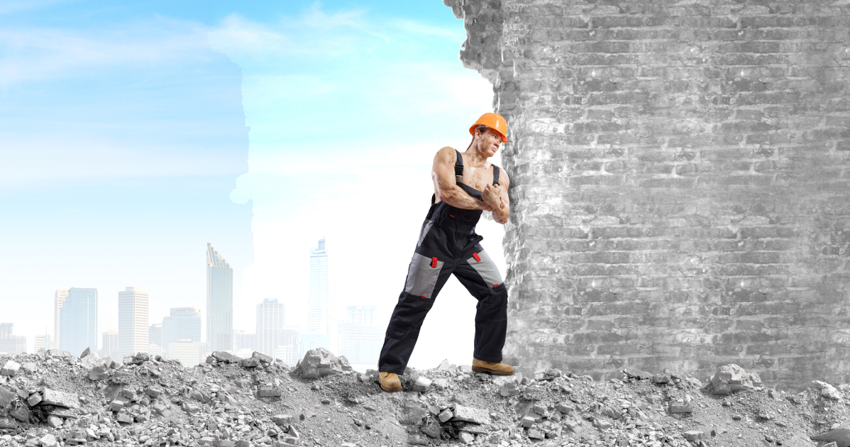 strong man in hard hat pushing on wall