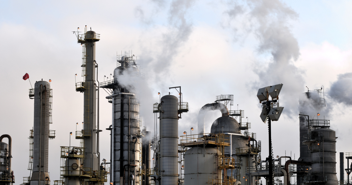  Pollution arches over the towers of a large oil refinery